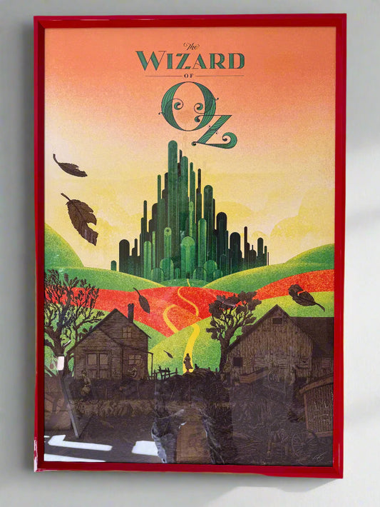A framed color variant screen print of 'The Wizard of Oz' featuring an artistic depiction of the Emerald City with trees, houses, and the character Dorothy in the foreground.