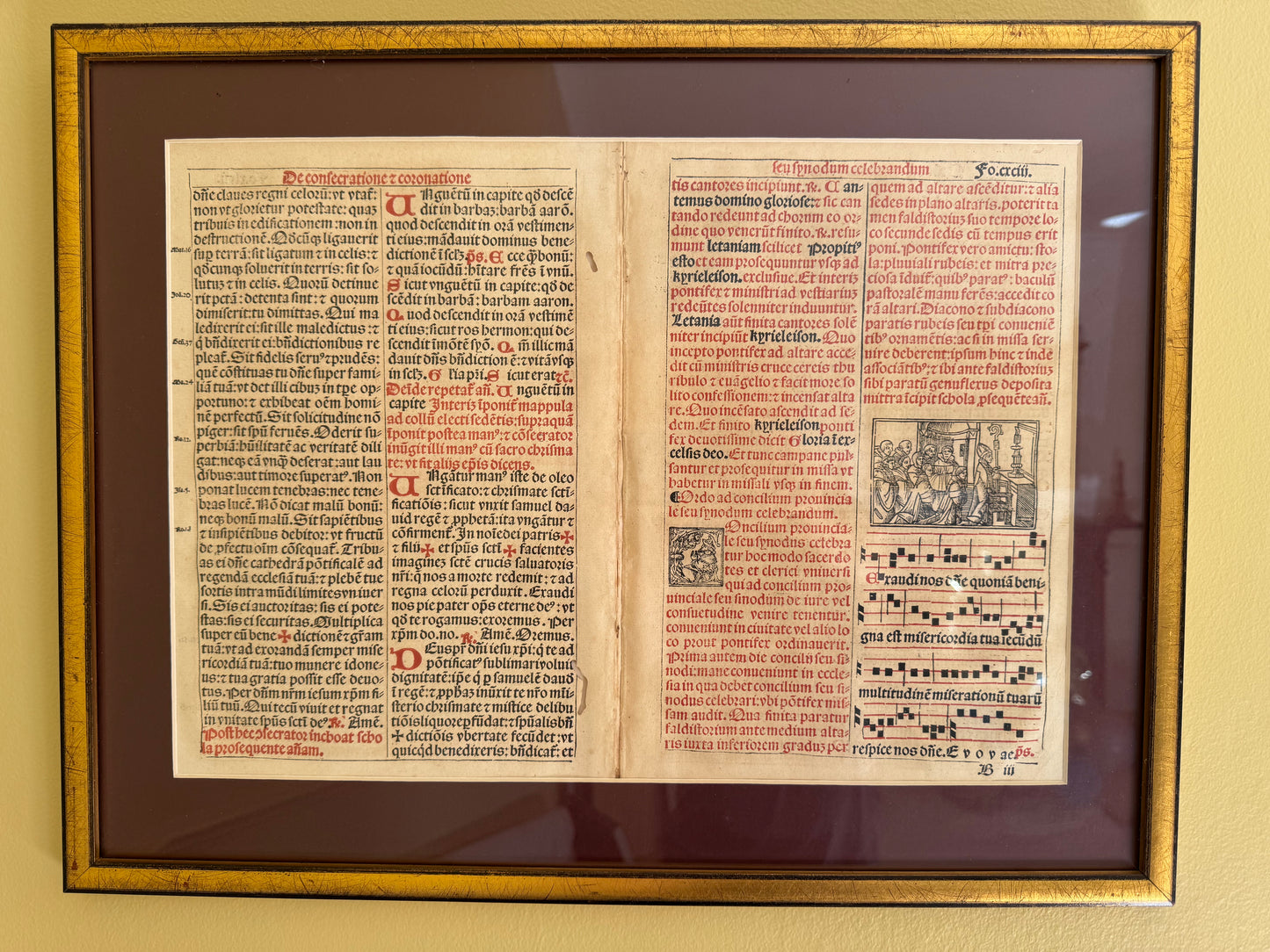 A framed and matted rare original print in Latin text from the 15th or 16th century, featuring images of musical notes and a religious church scene.