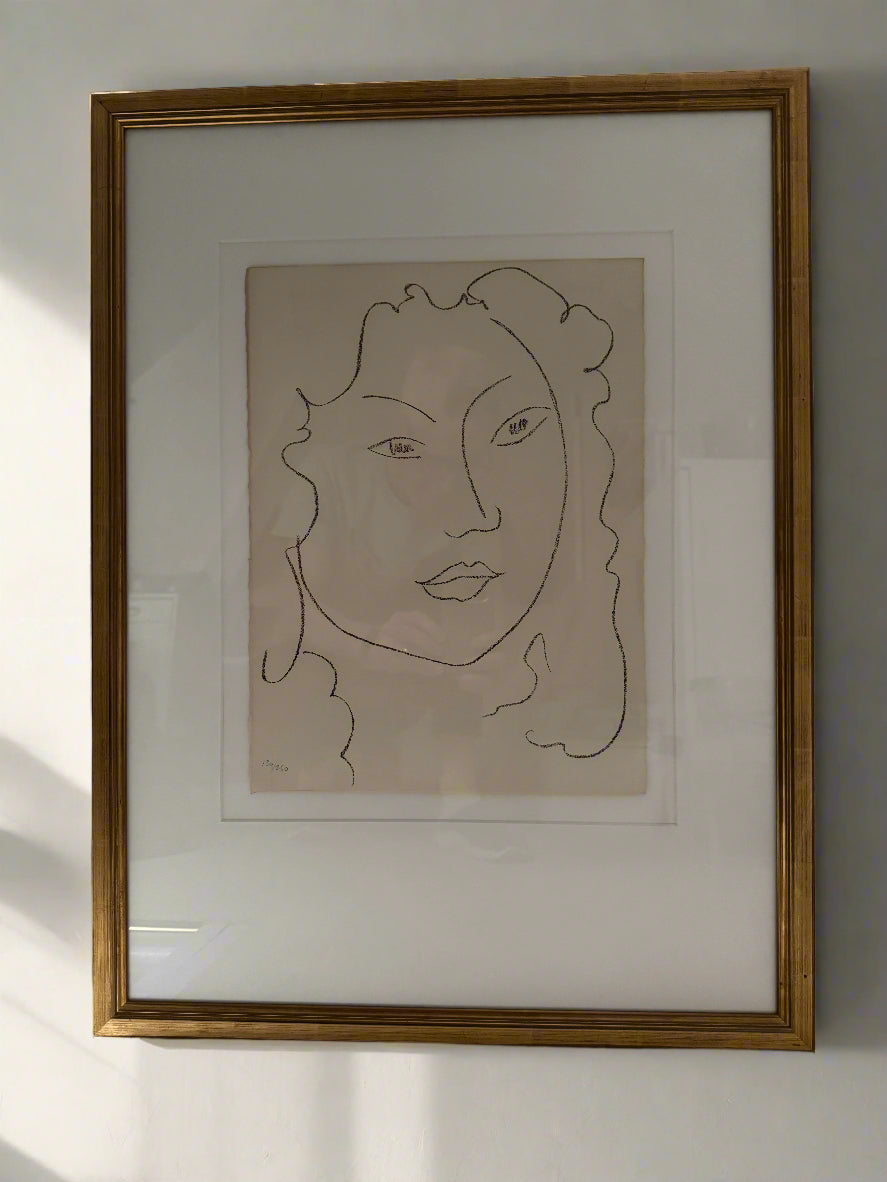 A framed and matted print of a simple portrait drawing of a young lady, titled 'La Petite Ile' by Henri Matisse.