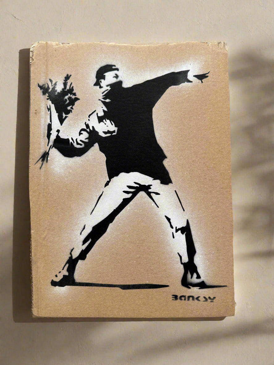 Stylized artwork of a figure in a dynamic pose on a cardboard background, resembling Banksy.