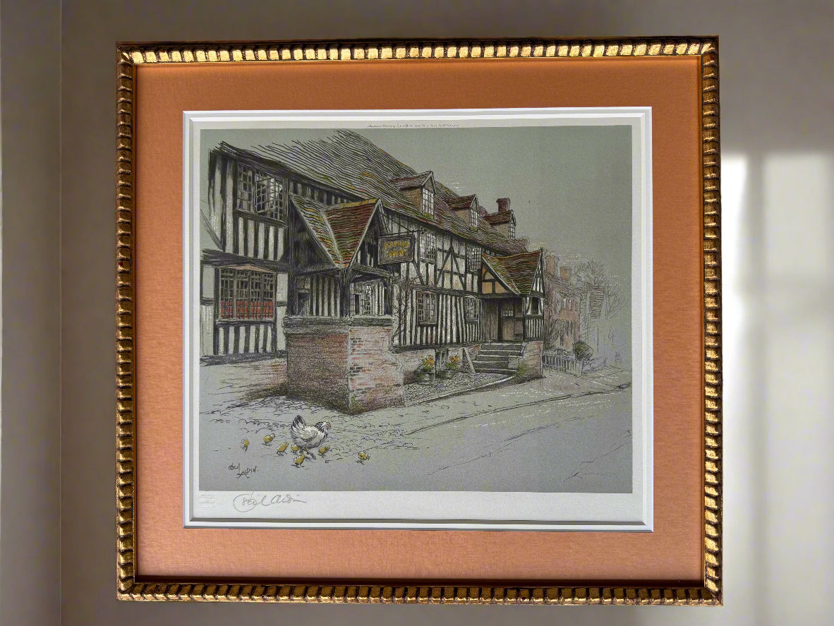 Framed colour artwork of a vintage village scene with half-timbered houses. 